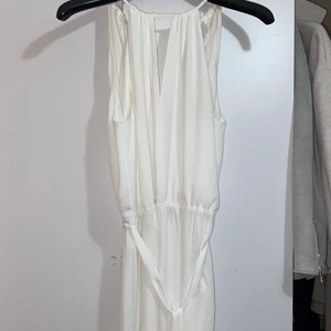 Vit playsuit - En vit playsuit från GinaTricot. Öppen i ryggen och knyte i midjan. Ärmlös. Använd en gång, strl.38