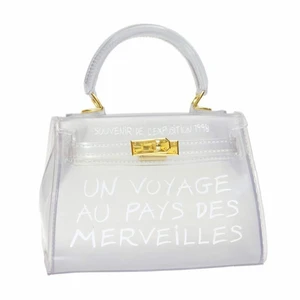 Axelbandsväska - Superfin Axelbandsväska som är i ett genomskinligt material med texten ”un voyage pays des merveilles”. Axelbandet är genomskinligt och väskan har även ett litet handtag. köpt i Belgien och använd en gång, alltså i mycket bra skick!!👜❣️   Frakt tillkommer!  #bags 