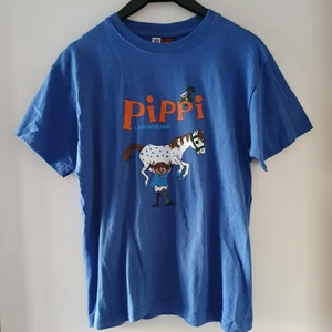 Vintage Pippi Långstrump t-shirt - Vintage blå t-shirt med Pippi Långstrump. Storlek 164 men passar ca storlek XS/S och även kanske liten M. Har lossnat pyttelite i trycket vid hästens rygg (se bild 2).Fraktkostnad blir 45kr.  OBS! Budgivning till lördag kl 17. Kommentera jättegärna bud vid intresse (med höjning på minst 5kr, exkl frakt) tack! 😊