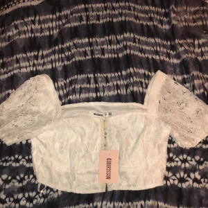 Missguided Spets Croptop - Superfin topp som fortfarande ligger i sin originalpåse. Ett felköp som glömts returneras. Har inte provats utan endast tagit ut för bild. Bygeldetaljer fram. Strl 42 men även denna lite liten i storlek. Nypris 250