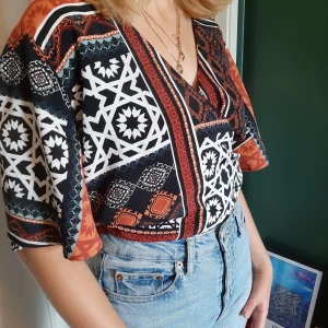 Cool blus🤎 - Blus med coolt mönster. Knyts i ryggen eller runt om som på bilden(knytningen göms enkelt). Köpt på second hand men i nyskick. Från ginatricot. Med tanke på knytningen så passar den på stora som små:)           Frakt tillkommer