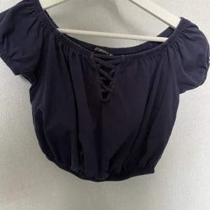 Terranova kroppad tröja. Fin marinblå färg i storlek xs.  - Croptop, off-shoulder, detalj framme, sitter åt i midjan. Blir en liten ballong liknande look. Kommer inte till användnign längre, köpt för ca 1 år sedan. 