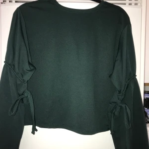 Tröja  - Mörk grön tröja med rosetter på armarna