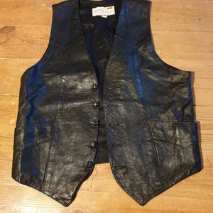 Skinnväst  - Svart skinnväst made in USA. Märkt Storlek 38 Längd fram 59 cm, bak 48 cm Armhåla till armhåla 44 cm  150:- plus frakt Spårbart 63:- 