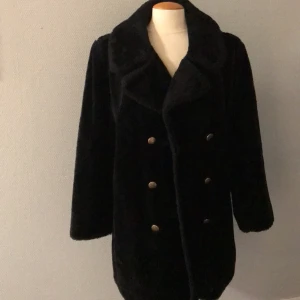 Kappa - Fodrad kappa i fejkpäls. Utrensad från vårt filmförråd och har endast använts i filmproduktioner. Lappen med storlek sitter inte kvar, men jag uppskattar att den är Medium. Mått kan skickas! 