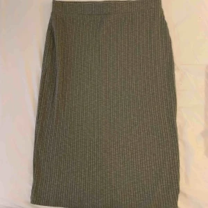  - Stickad kjol i militärgrön, går strax nedanför knäna på mig och jag är 168cm lång. Aldrig använd! 