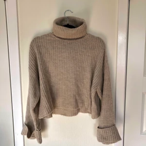 Stickad tröja  - Beige stickad tröja från Gina Tricot i storlek S med hög krage och vida ärmar nertill. Kan mötas upp i Malmö annars tillkommer fraktkostnad 