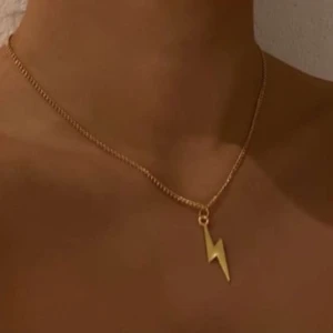 Halsband, smycken  - S09. Jättefint halsband i guld med en blixt på. Glöm inte att 10% av vinsten går oavkortat till organisationen kvinna till kvinna.