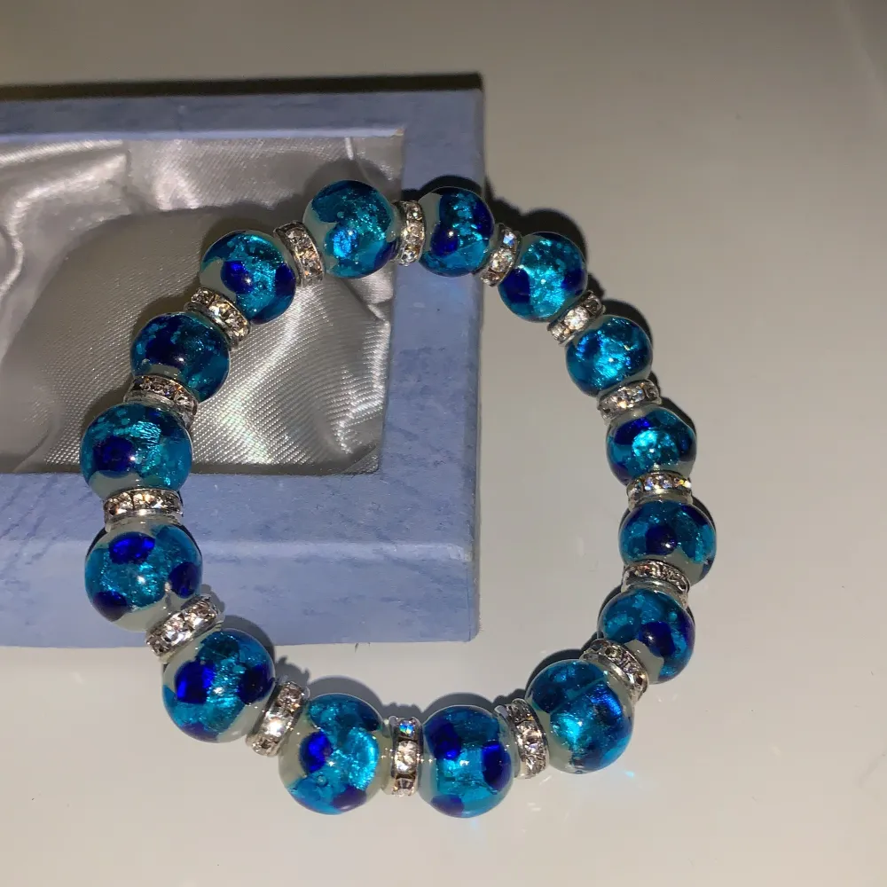 Detta är ett helt nytt och oanvänt armband som också kommer med en jättefin box, det finns flera olika blåa nyanser i stenarna på armbandet och flera små diamanter. Jättefint armband och speciellt om man tycker om blåa smycken. Jag valde att sälja det efter detta inte är min stil. . Asusteet.