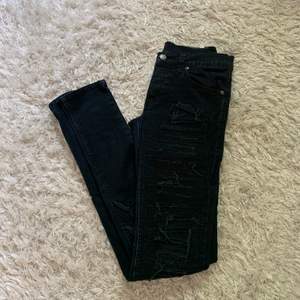 Snygga mörkblå tighta jeans med slitningar längs benen både bak och fram