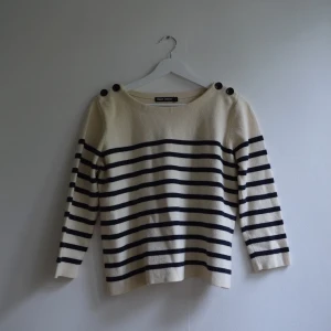 Stickad tröja - En stickad tröja från Filippa K. Fortfarande i jättebra kvalite trots använd. På axlarna finns fina detaljer av knappar. Ärmarna är trekvartslånga och färgerna är ljusbeige och svart. Frakt 59kr 🌸