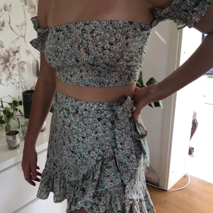 Two piece set  - Ett tvådelat set i boho stil med blommor. Finns knappar i magen på kjolen och stängs även med bandet. Toppen har resår i ärmarna och även bak i ryggen. Ej använd. 