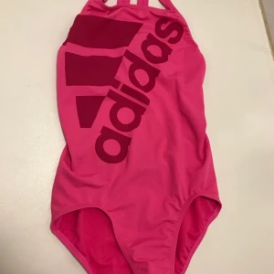 Baddräkt Adidas - Säljer denna rosa baddräkt från adidas. Den är köpt i London, endast använd 1 gång, så i nyskick!💗 Frakt tillkommer!
