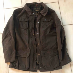  - Oljejacka ifrån Barbour i mörkbrunt. Tillhörande fuskpälskrage som man sätter på med knappar på insidan av jackkragen. Fint skick! 