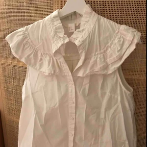  - Kortärmad skjorta med detaljer i krås. Köparen betalar eventuell frakt.