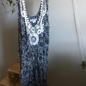 Spräcklig klänning  - Spräcklig klänning (marinblå). Slutar i mitten av låret. Spets detalj i halsen. Bra skick. 