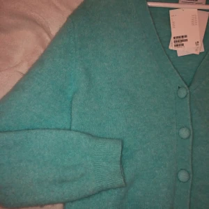 Turkos stickad tröja med knappar  - Stickad tröja med knappar från another stories. Köpt för några månader sedan, men aldrig använt. Storlek m. Nypris: ca 800. Priset går att diskutera :) 