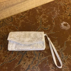  Silvrig Plånbok -  En Silvrig plånbok ganska sliten jättebra jättefin väldigt många fack så jättemycket grejer får plats