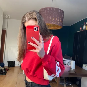 Croppad tröja - En röd croppad tröja med 2 vita ränder på vardera sida ifrån hm storlek M men skulle säga att den mer är en S