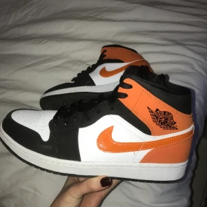 Air Jordan 1 Mid  - Jag säljer mina Air Jordan 1 Mids. Endast använda två gånger pga beställda i fel storlek. Den orangea färgen ser väldigt ljus ut på bilderna pga blixten, den sista bilden visar de egentliga färgerna. Originalpris ca 2300 kr. Pris går att diskuteras! 😋