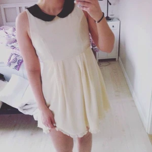  - Beige klänning med svart krage som knäpps där bak. Endast använd en gång, så i väldigt bra skick. Köpt för 500kr, men säljer den för endast 120kr! Frakt tillkommer med 20kr och betalas av köpare.