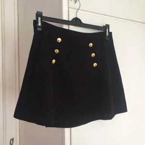  - Svart kjol med gulddetaljer. Dragkedja med spänne på sidan. Nyskick! 