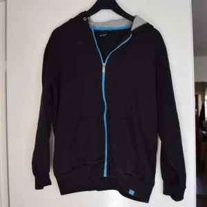  - Munkjacka i svart med blå dragkedja i märket SOC, barnstorlek 158/164 men passar en xs-m i vuxenstorlekar.