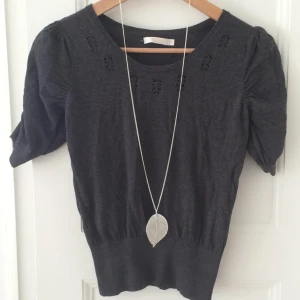  - Mycket söt kort grå topp ifrån Wera med puffärm. Markerar midjan på ett mycket fint sätt. Frakt tillkommer, har swish. Halsband ingår ej.