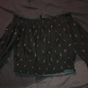 Storlek xs - En ny tröja från H&m väldigt bra och fint skick, svart med röda roser på! Är en axeltröja så att man visar axlarna