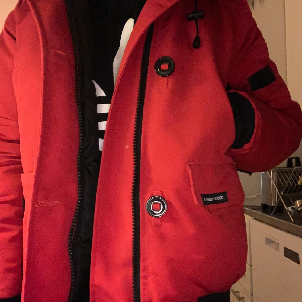 En röd Canada Goose jacka i modellen chilliwack bomber. Har 5 fickor, dragkedja samt knappar. Storlek M men själv har jag S, passar i båda storlekarna. Använd ett fåtal gånger i mycket gott skick. Skriv vid intresse!  Original pris 9300kr, säljes för 4500kr. . Jackor.