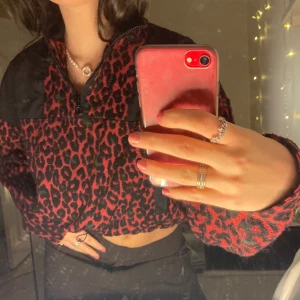 Geopardmönstrad fleece tröja  - Assnygg fleece tröja i geopardmönster i rött, svart och grönt! Finns en kort dragkedja där fram och det går att dra åt i midjan så att tröjan sitter mer croppat:) köpt på Urban outfitters