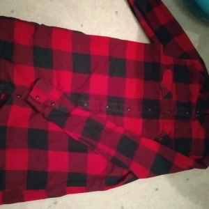  röd svart Skjorta - Säljer en röd svart randig skjorta köpte för ett år sen men har knappt användt den 