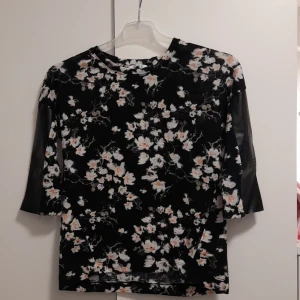 Blommig blus  - En blommig blus från Cubus i strl 146/152. Fina skinnimitationsdetaljer på varsin ärm. Blusen är i använt men fint skick. Köparen står för frakten 