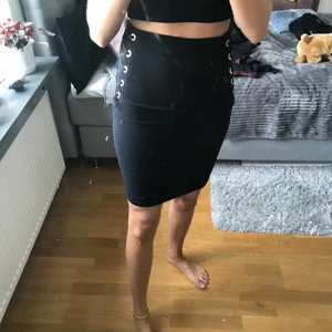 Svart knälång kjol - Säljer denna jättefina knälånga kjol med detaljer på sidorna, frakt tillkommer