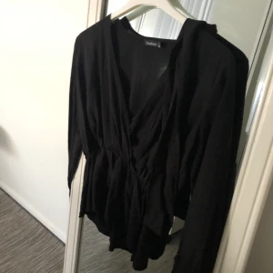 Svart blus  - Svart blus med knut runt midjan i storlek 36 (S) från boohoo. Aldrig använt, därmed bra skick. Frakt förekommer, men kan mötas i Göteborg. För fler frågor och bilder kontakta mig!