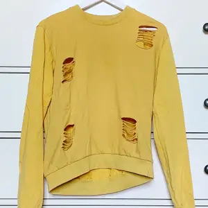 En sweater med klippta hål (hålen är med i originalplagget). Fräsch gul färg och baggy passform. Passar S-M beroende på hur man vill att den ska sitta. Sparsamt använd💕 Pris kan diskuteras och köparen står för frakt❣️