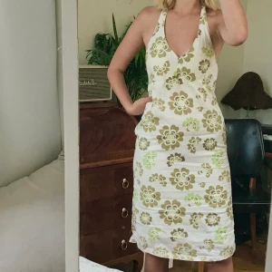 Grön-blommig klänning - Grön blommig sommarklänning!! Knyts i nacken så - anpassbart. Sitter tajt vid mina höfterna. Kan skriva mått om de önskas. Har satt en säkerhetsnål i ryggen för att kunna anpassa hur tajt man vill ha den i midjan! Möts på söder, frakt tillkommer!💞💞💞