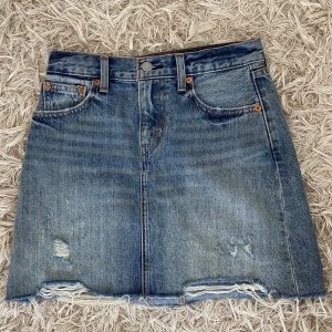 Levi’s Jeanskjol med slitningar 💙 - Säljer denna supersnygga ljusblåa jeanskjol från Levi’s som använts ett fåtal gånger bara. Passar till allt! Storlek 24 i midjan men jag som brukar ha 25 kan ha denna också. 
