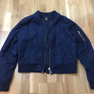 Marinblå Bomerjacka Cubus - Säljer den här fina, marinblåa bomberjackan med gulddetaljer från Cubus. Den är i storlek M och den är enkel att styla med! Säljer den för 70kr, köparen står för frakt! 💟 