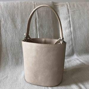 Benvit/ljus beige liten men rymlig bucketbag.  Hämtas upp i Stockholm eller köpare står för frakt.