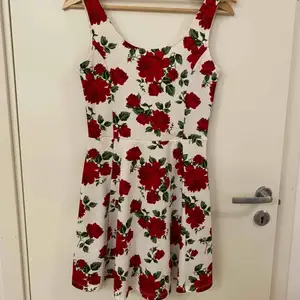 Stretchiga klänning med ros mönster. Utsvängande kjol med lite längre öppning på ryggen. Aldrig använd 