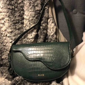  - Skitsnygg mörkgrön väska från Nakd. Rymlig, lätt att stänga och reglerbart band. 