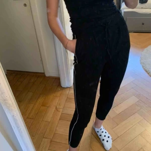  - Avslappnad svart byxa i mjukt bomullsmaterial med en vit rand på varje sida. Priset är exklusive frakt 