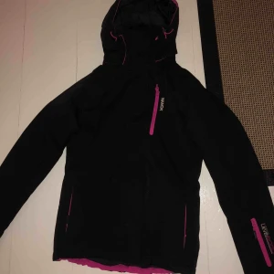  - En rosa svart skidjacka från Nanok. Jättefint skick. Använt 2 gånger, skriv om du är intresserad!! Frakt ingår ej.