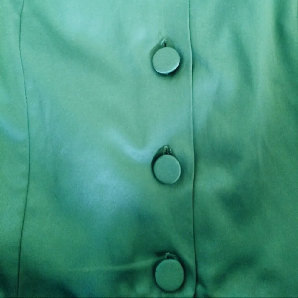Kort klänning i ett blankt grönt tyg. Klänningar.