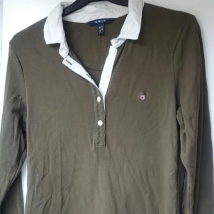  - Militärgrön jersey med cremevit krage i 100% bomull. Bra skick och ser fräsch ut. Är mer grön än på bilden. Jätteskön. Passar den som har strl 38-42 skulle jag säga. Stretchig. Nypris 899kr 