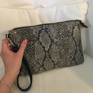 Söt clutch  - Fin clutch i ormskinnsmönster med små detaljer, har fler fack och är perfekt festväska. Går även att fästa band eller kedja. Köpt i Paris för ca 400kr 