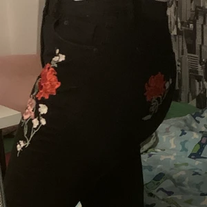 Svarta jeans med broderade rosor - Oanvända svarta jeans från H&M med broderade rosor på. Aldrig använda då de är för korta och för små :( Står stl 42 men tycker de borde passa 38/40