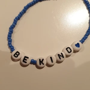 Armband - Ett blått hemmagjort armband, där det står "be kind" med ett blått hjärta, är gjort med elastiskt band så passar alla! 💙