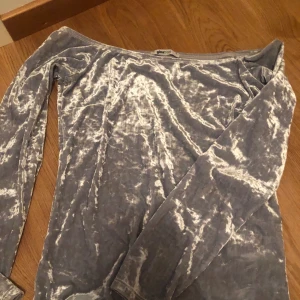 Offshoulder topp storlek M - Långärmad offshoulder topp. Silver-färgad med lite blå/kalla nyanser. Använder aldrig då jag föredrar guld mer än silver. Endast använd 1 gång. Köpt på Ginatricot för 3 år sedan. Frakt: 30 kr